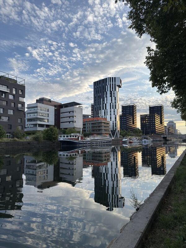 Moderne Wohn- und Bürohäuser an einem Kanal, die sich im ruhigen Wasser vollständig spiegeln
